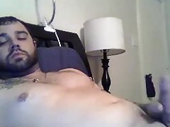 Sexy tattooed guy shooting on bed
