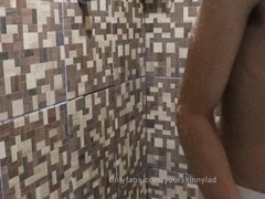 Bony teenager is taking douche in white trunks