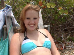 A smiling blue eyed honey is playing with a dick on the beach
