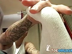 Tattooed guy massages his feet and uses socks on his cock