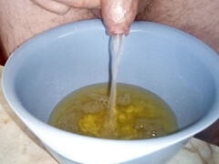 Close up when John is peeing into a plastic bowl